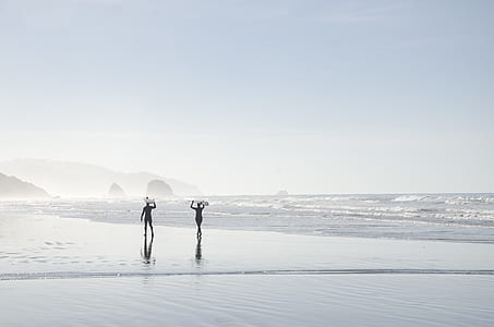 two person walking by the seashore during daytime thumbnail