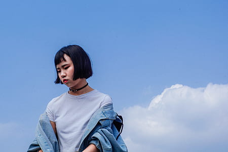 woman wearing white crew neck t-shirt and blue denim jacket while standing under clear blue sky thumbnail