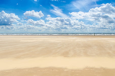 white brown sand near shore under white clouds and blue sky during daytime thumbnail