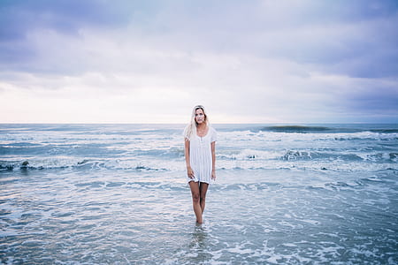 woman with white hair in white dress standing on seashore thumbnail
