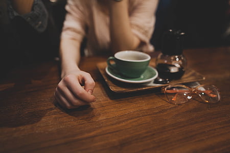 person wearing beige top sitting beside brown wooden table thumbnail