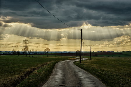 gray road between green grass at daytime thumbnail