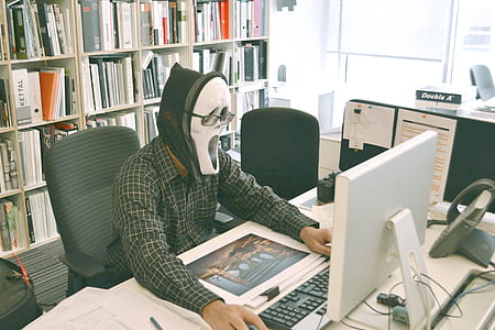 person wearing ghost mask while using computer desktop thumbnail