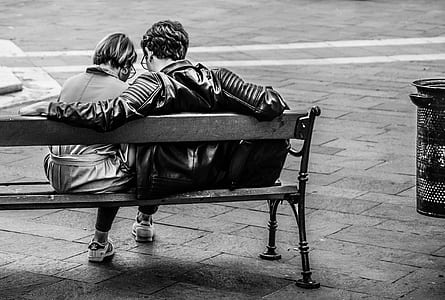 grayscale photo of male and female sitting at bench thumbnail