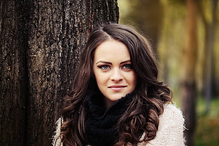 woman in white coat standing in front of tree thumbnail