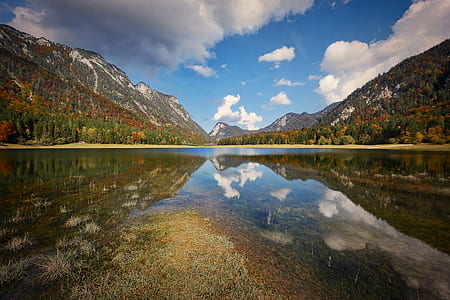 body of water near mountain during daytime thumbnail