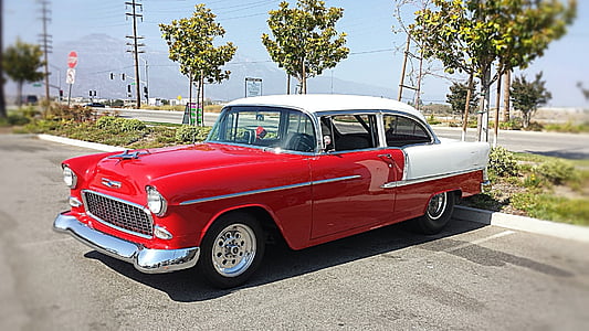 classic red and white coupe park near green leaf tree thumbnail