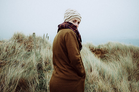woman wearing coat standing on grass field thumbnail