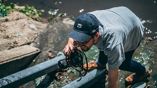 Man Holding Dslr Camera Wearing Cap thumbnail