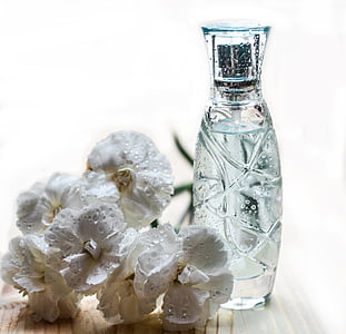 white carnation flowers beside clear cut-glass bottle close up photo thumbnail