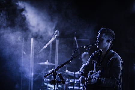 man playing the guitar and singing on stage thumbnail