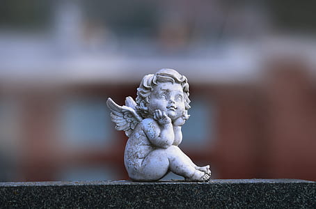 selective focus photography of angel figurine sitting while hands on chin thumbnail