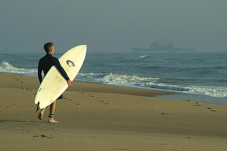 man carrying white surfboard standing on shore during daytime thumbnail