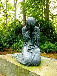woman kneeling concrete statue near trees thumbnail