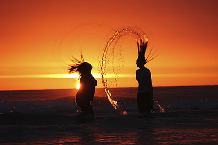silhouette of two women on body of water at golden hour thumbnail