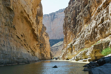 brown cliff and body of water during daytime thumbnail
