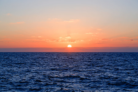 sunset at horizon over body of water thumbnail