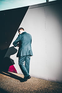 man walking beside gray steel wall thumbnail