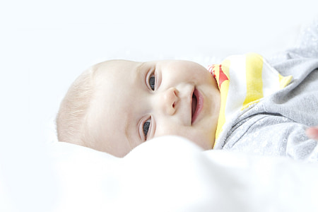 smiling baby lying on white textile thumbnail