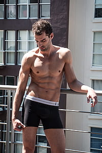 topless man leaning on gray steel fence thumbnail