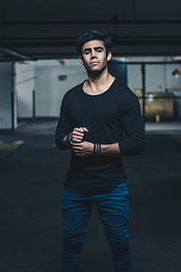 man wearing black scoop-neck long-sleeved shirt standing inside building thumbnail