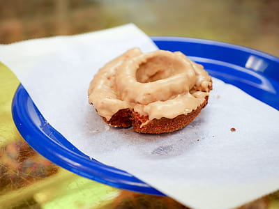 A maple cake donut sitting on a blue plate. thumbnail