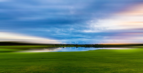 green grass field near body of water during daytime thumbnail