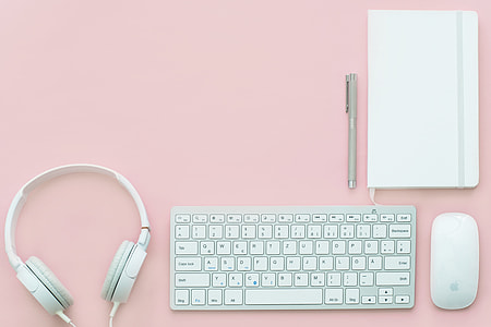 white earphones, wireless computer keyboard, Apple Magic Mouse on table thumbnail