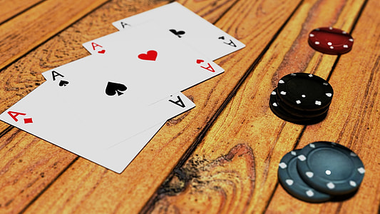 four aces playing cards on brown wooden surface thumbnail
