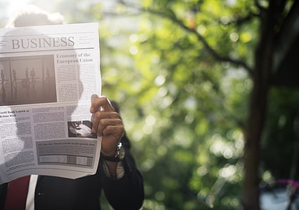 man reading business section of newspaper thumbnail