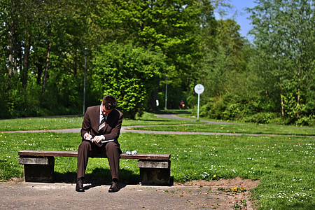 man wearing black suit jacket sitting on brown concrete bench thumbnail