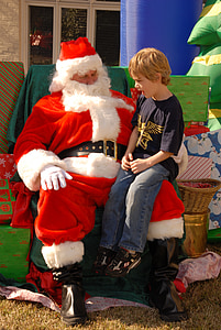 man in Santa Claus costume carrying boy thumbnail