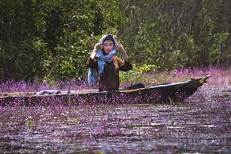 woman riding boat near purple petaled flowers thumbnail