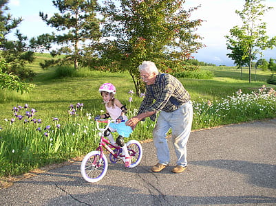 man helping girl to ride bicycle thumbnail