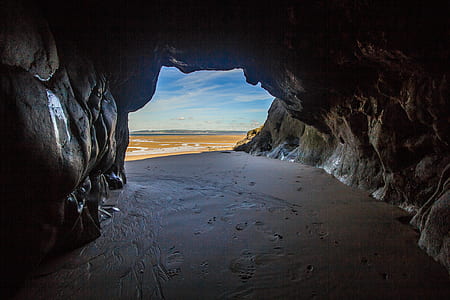 brown cave in front of body of water thumbnail