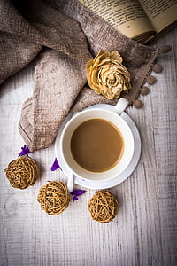 white ceramic mug filled with brown beverage near brown textile and book thumbnail
