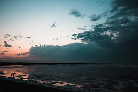 silhouette of man and woman standing on sea shore during sun set thumbnail