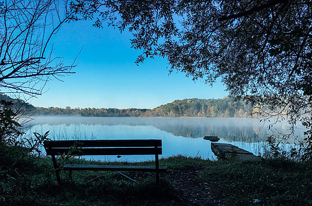 photo of bench near a lake under blue sky thumbnail