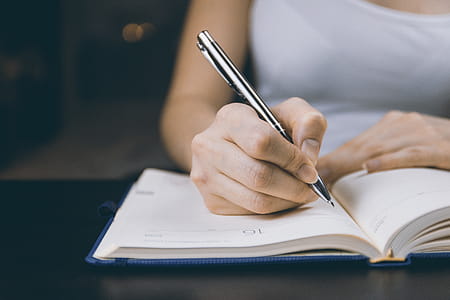 The woman’s hand holds a pencil and writes a plan into a diary at home thumbnail