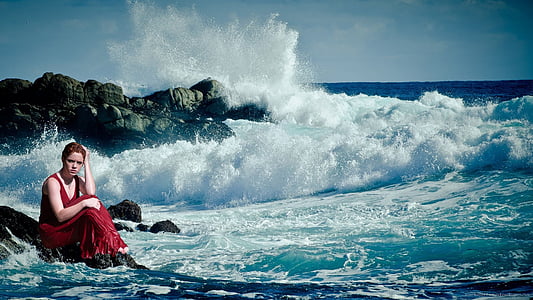 woman sitting on rock near body of water thumbnail