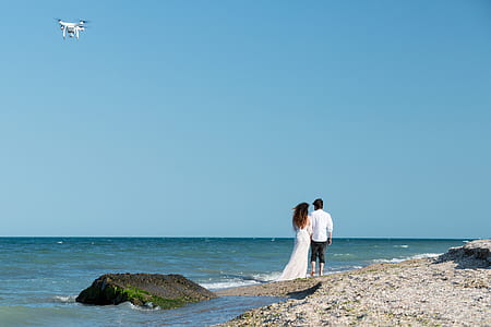 man and woman standing at beach shore thumbnail