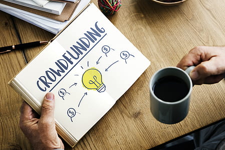 Person Holding Crowdfunding Book and Cup of Coffee thumbnail