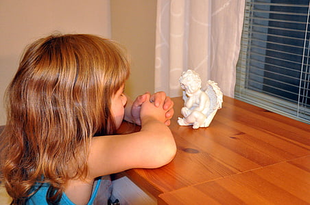 girl praying in front of cherub figure thumbnail