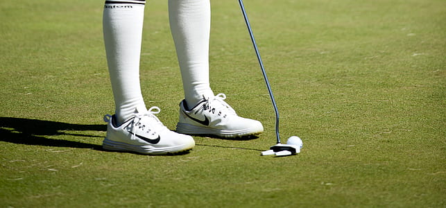 person aiming golf ball with golf putter on green grass at daytime thumbnail