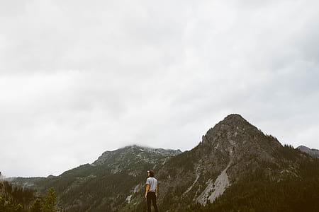 person standing on cliff facing mountain thumbnail