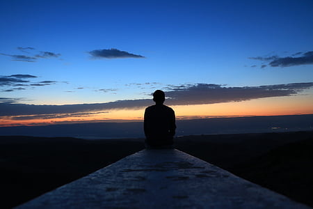 man sitting on edge of concrete pavement looking at view thumbnail