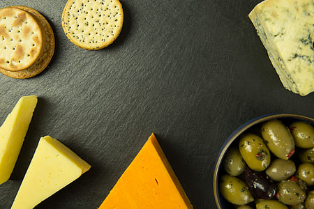 Overhead shot of cheese, olives and biscuits on a slate board thumbnail