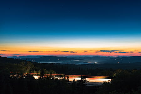 landscape photography of body of water and hills during golden hour thumbnail