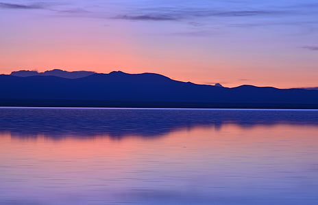 mountain range near water under blue sky thumbnail