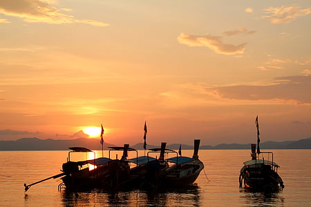 silhouette of four boats on body of water thumbnail